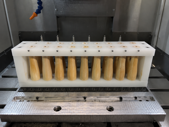 Wooden branding-iron handles held in a fixture on a machine bed